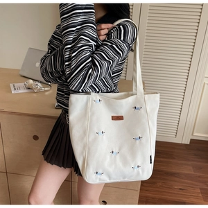 Detail of white canvas tote bag featuring dachshund embroidery and leather logo patch