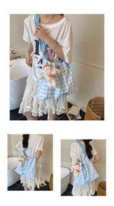 Detail of blue gingham drawstring tote bag with cute white puppy plush charm pendant