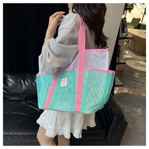 Close-up of mesh tote bag with green mesh and pink straps worn on the shoulder