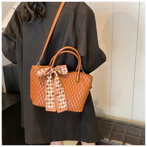 Detail of caramel brown tote bag with wave pleated texture and elegant silk scarf handle