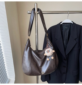 Dettaglio della borsa tote in pelle PU marrone scuro con logo e ciondolo a cucciolo