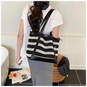 Close-up of black and white striped mesh tote bag with durable black leather shoulder straps