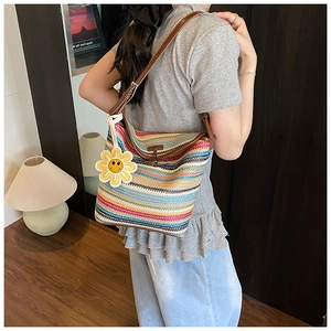 Detail of colorful striped woven straw tote with brown leather strap and sunflower charm