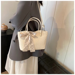 Close-up of cream tote bag with pleated leather texture and stylish bow scarf handle