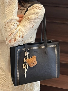 Elegant black faux leather tote bag with gold studs and cute bear charm on a model