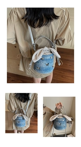 Vue détaillée du sac seau en denim bleu avec patchs papillon et cordon de serrage oreilles de lapin