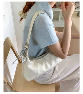 Dettaglio della borsa hobo in pelle bianca con ciondolo a farfalla in argento decorativo