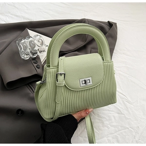 Detail of mint green striped handbag with silver metallic twist lock and smooth handle