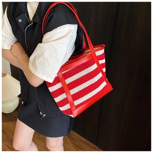 Detailed view of red and white striped woven tote bag with premium leather straps