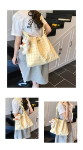 Detail of yellow gingham tote bag featuring a drawstring closure and plush dog charm
