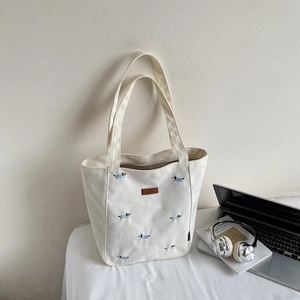 Close-up of cute dog embroidery and premium leather patch on white canvas tote bag