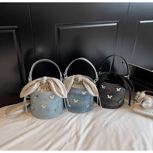 Détail des sacs seau en denim avec breloques papillon en bleu clair, bleu foncé et noir