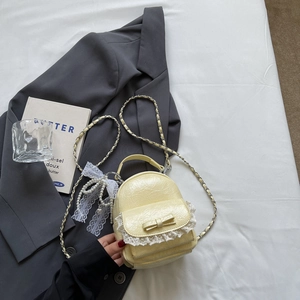 Détail d'un sac à dos en cuir plissé jaune avec bordure en dentelle blanche et nœud