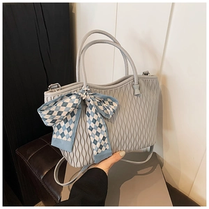 Detail of light blue pleated tote bag featuring a large blue checkered ribbon bow