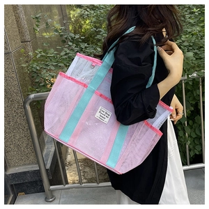 Detail of pink and white mesh beach bag with blue handles shown being worn by a model