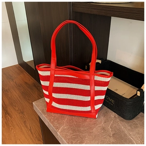 Detail view of red and white striped woven tote bag with durable red leather handles