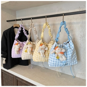 Detail of four colorful checkered drawstring tote bags with cute bunny pendants