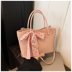 Detailed view of pink tote bag with vertical pleated texture and decorative silk scarf handle