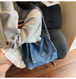 Close-up of a large blue denim tote bag with silver metal clasp and chain shoulder strap