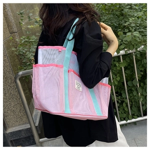 Pink and mint green mesh tote bag with multi-pocket design worn by a model on shoulder