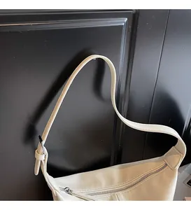 Détail de la fermeture éclair argentée et de la bandoulière du sac hobo blanc crème