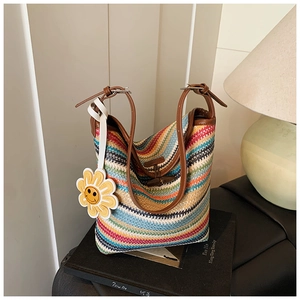 Detail of colorful striped straw tote with leather handles and sunflower charm