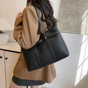 Large black pebbled leather tote bag for women shown as a stylish crossbody on a model