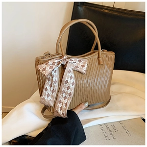 Close-up of brown textured tote bag with wave pattern and checkered ribbon decoration