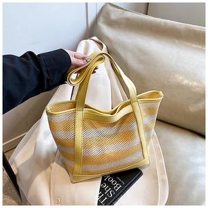 Detail of a yellow and white striped woven tote bag with adjustable shoulder strap