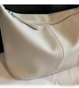 Gros plan sur la texture du cuir grainé beige et la fermeture éclair en métal argenté