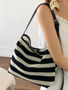 Black and white striped knit tote bag with horn buckle closure shown on model shoulder