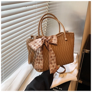 Detail of brown pleated tote bag featuring vertical wave texture and a checkered silk scarf
