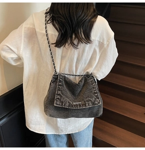 Detail of grey washed denim tote bag with silver chain strap and frayed edges design
