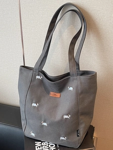 Minimalist dark grey canvas tote bag with cute dog embroidery on a gift box background