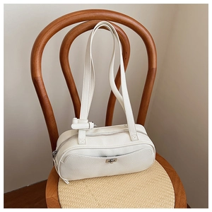 Nahaufnahme einer weißen Lederhandtasche mit Lychee-Muster auf einem Vintage-Holzstuhl