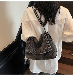 Detail of dark grey washed denim tote bag with silver chain and leather woven strap
