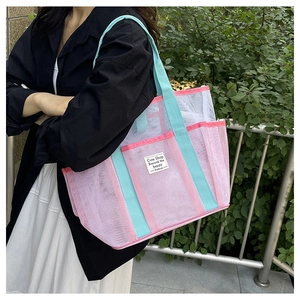 Detail of pink mesh beach bag with blue straps and white label for summer swimming