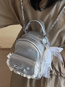 Mini sac à dos argenté métallisé avec dentelle et détail de nœud porté par un mannequin