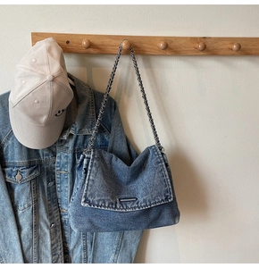 Detail of vintage washed blue denim tote bag with silver chain strap and metal buckle
