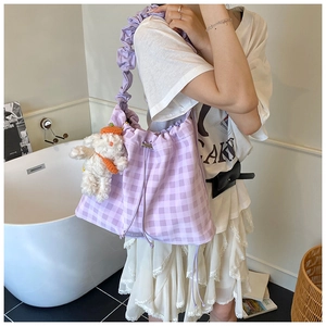 Detail of purple plaid drawstring bag with ruffled strap and plush dog keychain