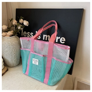 Detail of multi-pocket mesh beach bag with mint green, white, and pink stylish panels