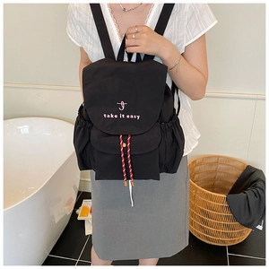 Dettaglio zaino in tela nera con ricamo rosa take it easy e coulisse a strisce bianche