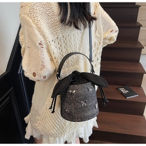 Détail d'un sac seau en denim gris avec papillons argentés et cordon de serrage oreilles lapin