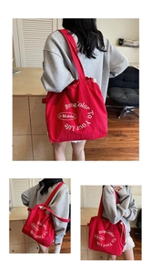 Detailed close-up of a red canvas tote bag with drawstring closure and printed quote