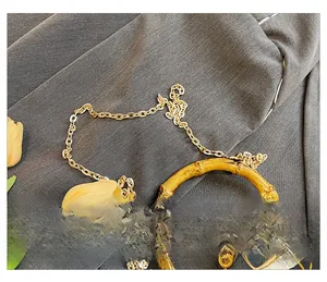 Detail of vintage satin handbag with bamboo handle, gold chain and metal frame clasp