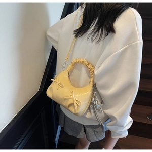 Close-up of cream yellow pleated dumpling bag with bow ties and star charm detail