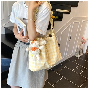 Detail of yellow checkered tote bag with ruffled strap and cute plush bunny charm accessory