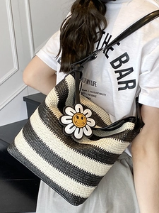 Woven black and white striped tote bag with yellow sunflower charm and leather straps