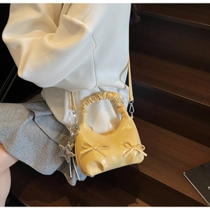 Detail of yellow glossy bow-knot handbag with star charm and pleats on a shoulder bag