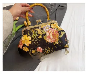 Detailed back view of vintage black silk handbag with bamboo handle and floral patterns